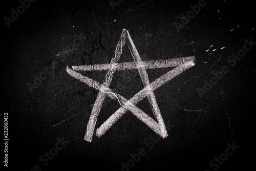symbol of a five-pointed star drawn in white chalk on a school blackboard