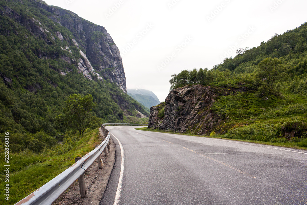 Mountain road. Landscape with rocks, sky with clouds and beautiful asphalt road in the evening in summer. Highway in mountains. Sweden