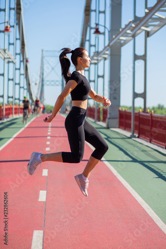 Pretty fit woman in sport apparel jumping during the workout. Empty space