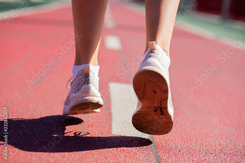 Closeup shot of female feet jogging at stadium in sun light