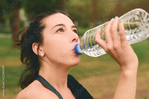 Portrait of sportswoman drinking water after workout