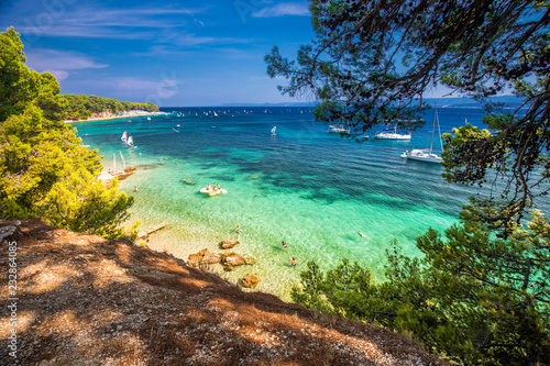 Seaside promenade on Brac island with pine trees and turquoise clear ocean water, Bol, Brac, Croatia.