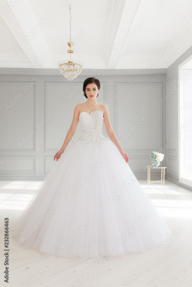 Young brunette bride in white luxury wedding dress. Classic studio interior, full-lenght portrait Young brunette bride in white luxury wedding dress. Classic studio interior, full-lenght portrait