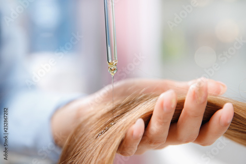 Obraz na plátně Master hairdresser applies oil to hair care for and restore growth of cuticles woman