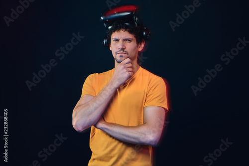 Portrait of a pensive male with bristle in yellow shirt wearing virtual reality goggles.