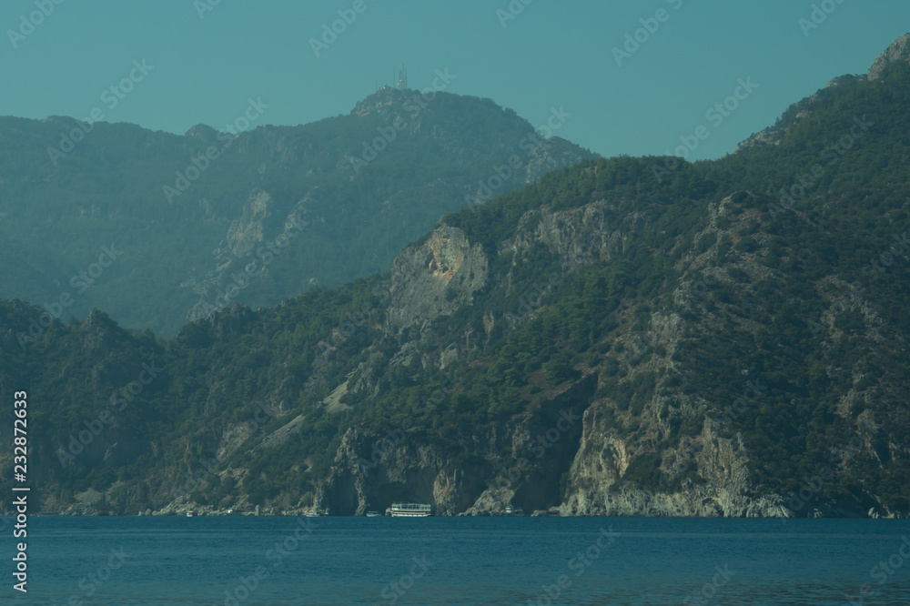 Mountain and sea. coastline with overgrown rocks Mountain and sea. coastline with overgrown rocks