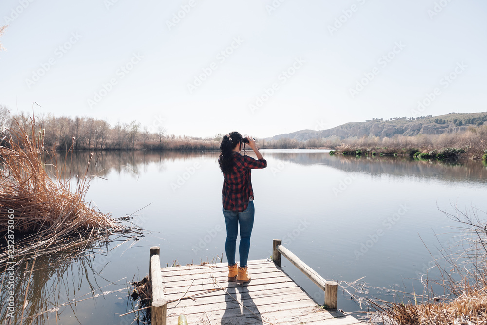 Young brunette woman on a jetty with binoculars
