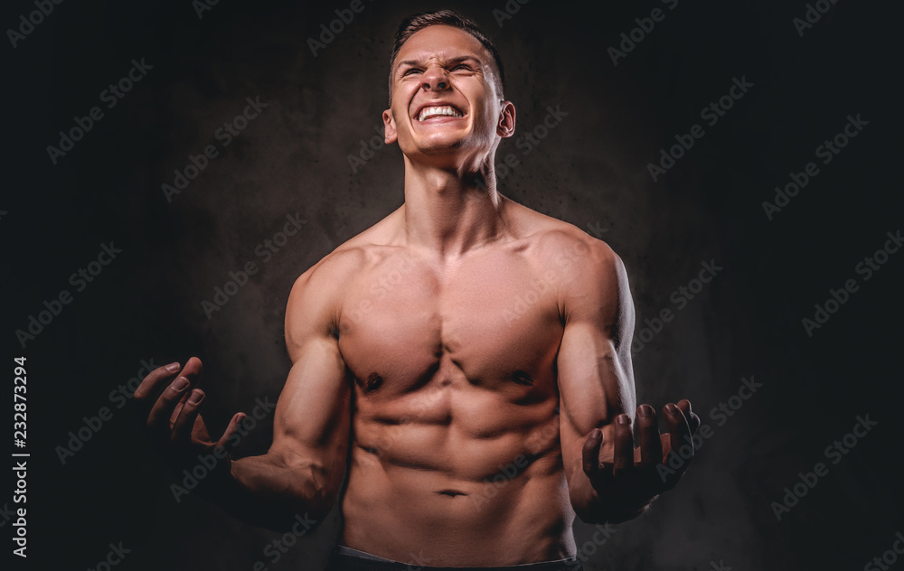 Portrait of an angry young man with a muscular body on dark background. Portrait of an angry young man with a muscular body on dark background.