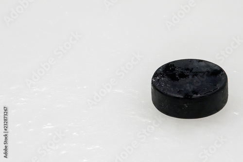 black hockey puck on ice rink. Winter sport.