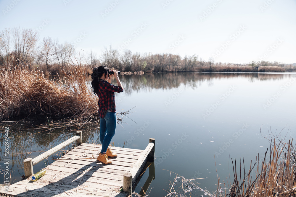 Young brunette woman on a jetty with binoculars