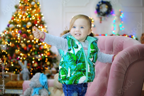Ребенок ждет чуда в Новый год. С новым годом! Счастливого Рождества! Новогодняя елка с рождественскими игрушками. Девочка на диване.
