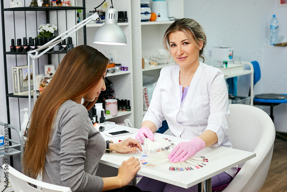 Obraz premium Manicure is happy to help his client girl in creating a beautiful manicure