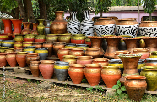 Clay pots stacked for sale on African roads. Pottery making place. Local craft market in Africa. Unique handmade colorful ceramic pots. Craftsmanship. African style. © Nataly Reinch
