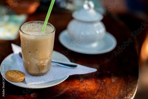 Glass of iced coffee with whipped cream on wooden background