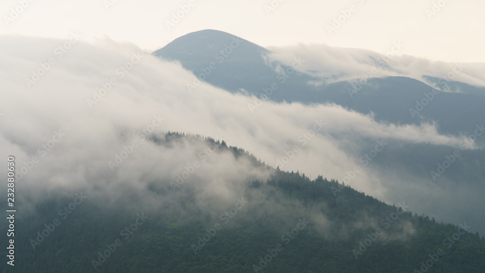 Beautiful morning panorama of forest fnd village covered by low clouds. Summer fog on the mountain hills. Misty woodland. Beautiful morning panorama of forest fnd village covered by low clouds. Summer fog on the mountain hills. Misty woodland.