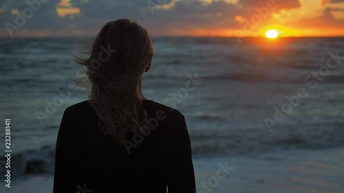 Girl relaxing in nature enjoying beautiful sunset landscape above the sea. Woman looking at ocean view at sunset thinking about life. 