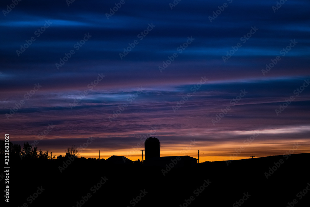 Fall sunrise with farm silos silhouetted
