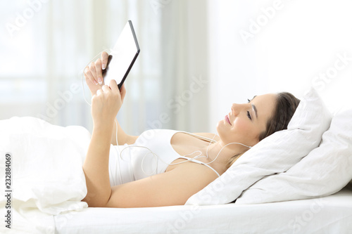 Lady watching media content in a tablet on a bed