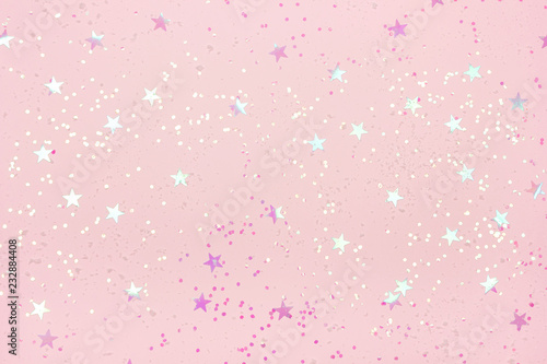 Beautiful pastel pink Christmas background with star shaped confetti. Top view. Copy space for your design.