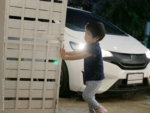 Little Asian baby girl, 34 months old, helps pushing / opening a house gate - children development by letting them do works by themselves