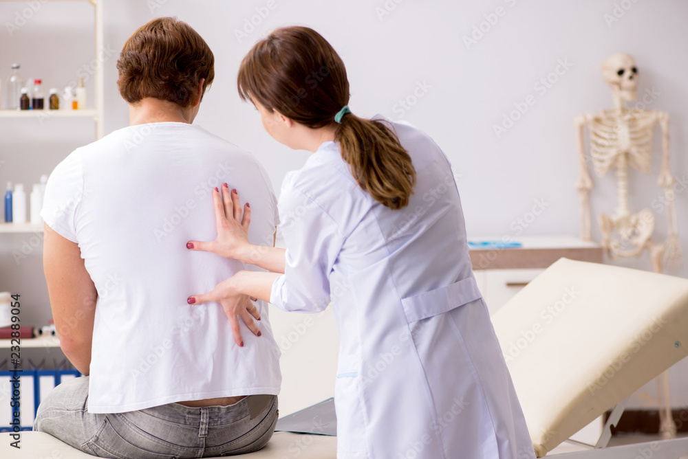 Fototapeta premium Male patient visiting young female doctor chiropractor 