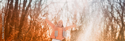 Happy winter fun woman playing throwing snow with arms up open in freedom enjoying the cold season