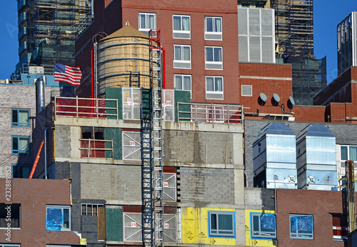 Photography Colorful facade of building exteriors with American Flag and water tower in Manh
