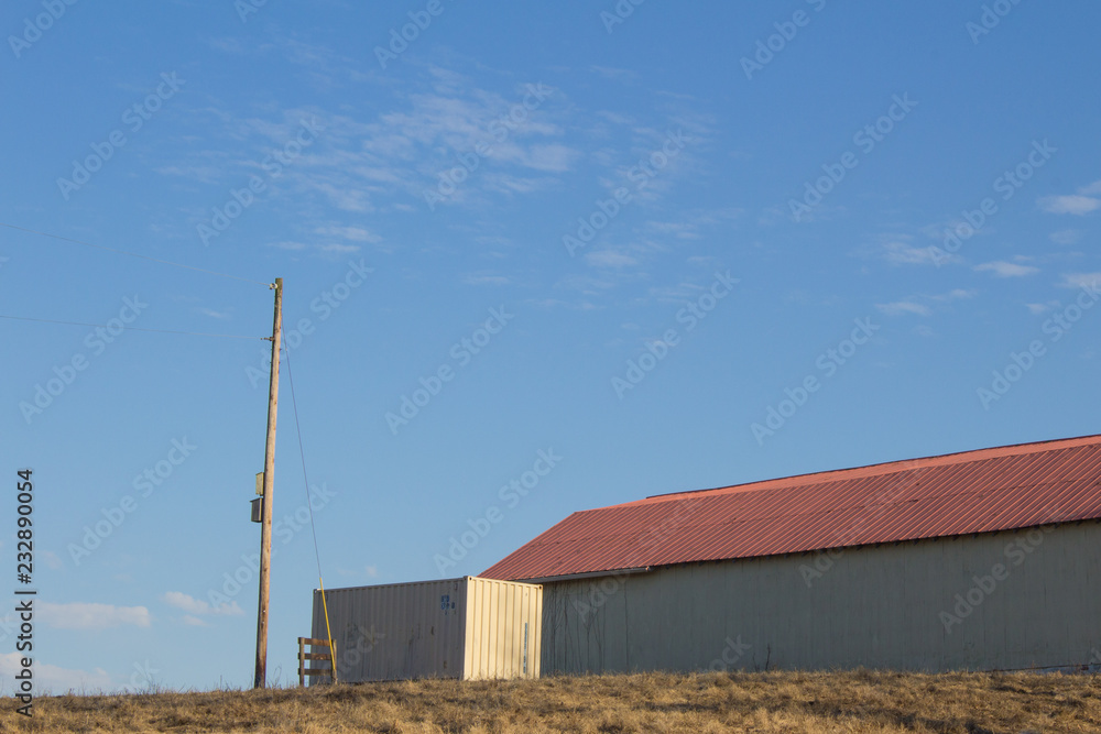 Exterior of a barn with red tin roof, blue sky, copy space, horizontal aspect Exterior of a barn with red tin roof, blue sky, copy space, horizontal aspect