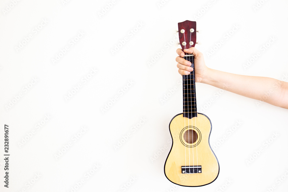 Obraz premium Women's hand holds the classic Ukulele close up with copy space in left side.