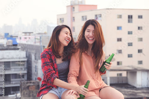 Young asian woman sitting and smiling at rooftop outdoor in urban city background, happy lifestyle