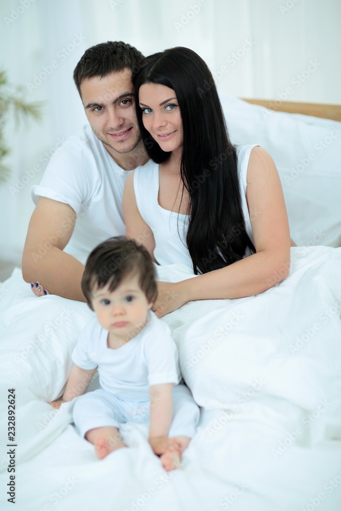 Cute little boy with parents on the bed