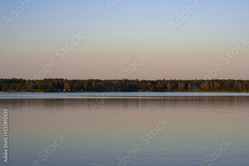 Blue lake with cloudy sky, nature series, a lake landscape with reflection from some trees. © IVA.FISCHER
