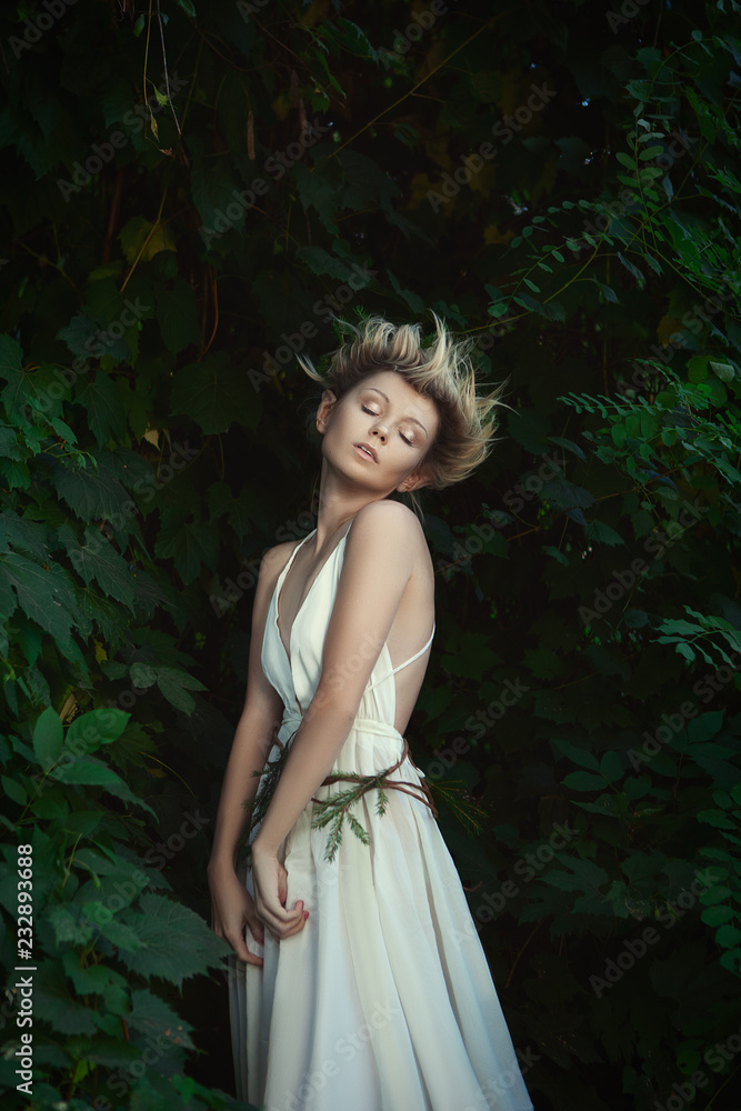 Young model is posing as a fairy in a forest 