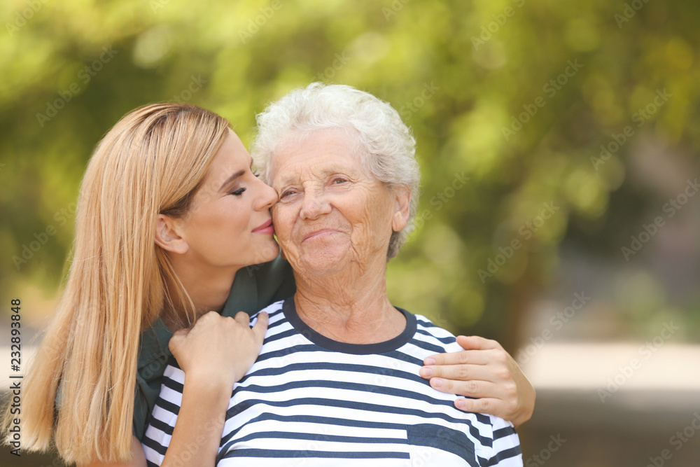 Woman with elderly mother outdoors on sunny day Woman with elderly mother outdoors on sunny day