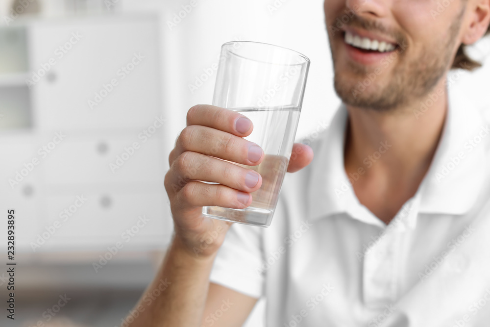 Young man holding glass of clean water indoors, closeup. Space for text Young man holding glass of clean water indoors, closeup. Space for text