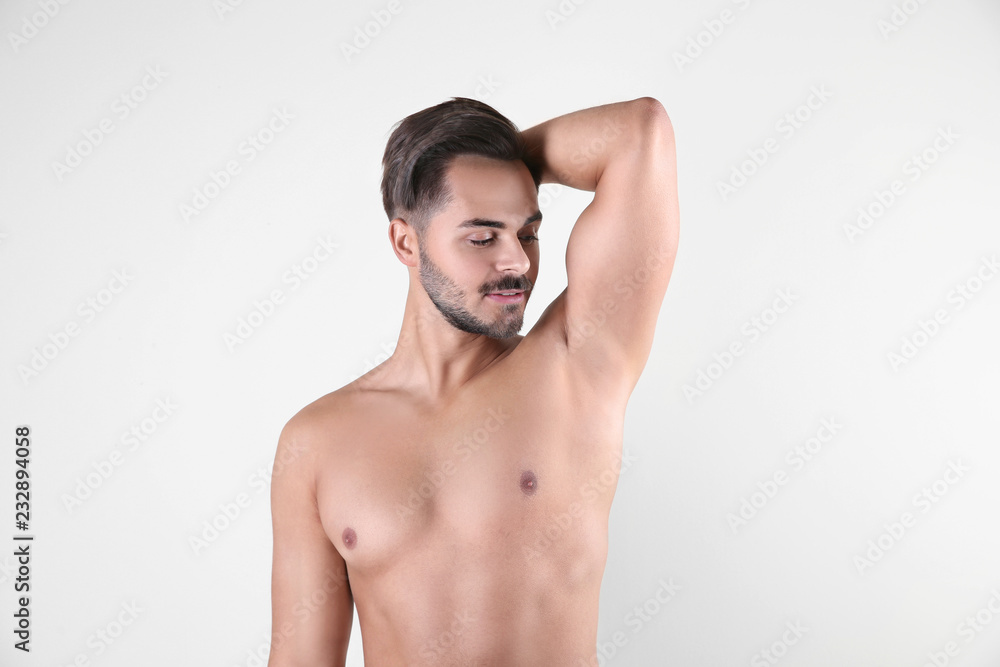 Fototapeta premium Handsome young man showing armpit on white background. Using deodorant
