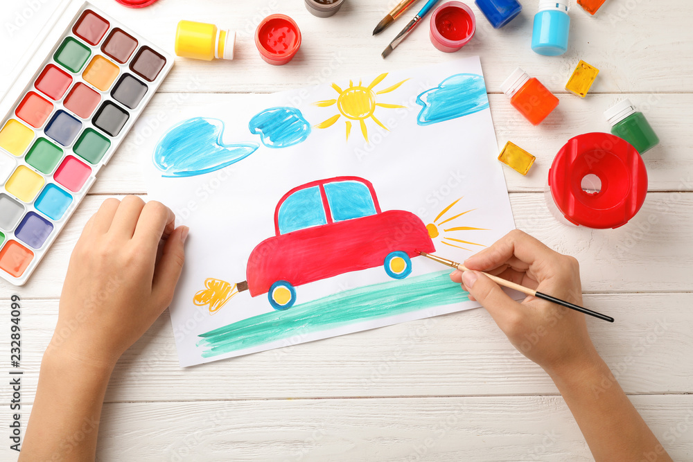 Fototapeta premium Girl painting picture of car on table, top view