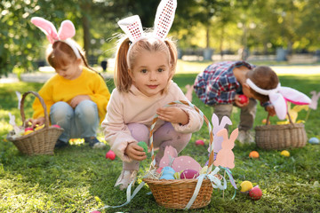 Cute little children hunting eggs in park. Easter tradition