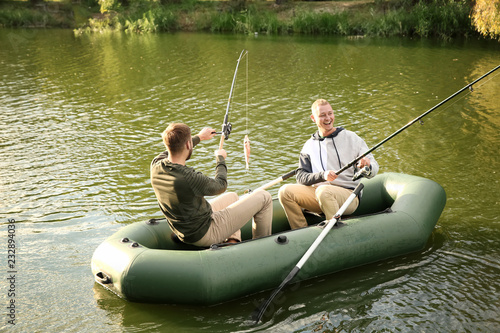 Friends fishing from boat on sunny day. Recreational activity