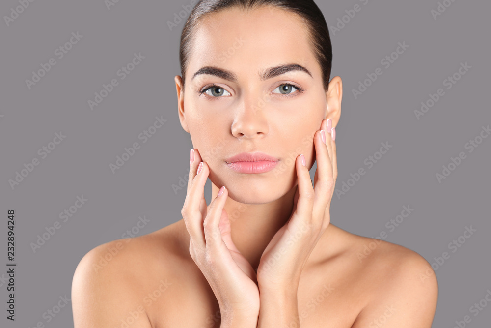 Portrait of beautiful young woman on grey background. Lips contouring, skin care and cosmetic surgery concept Portrait of beautiful young woman on grey background. Lips contouring, skin care and cosmetic surgery concept