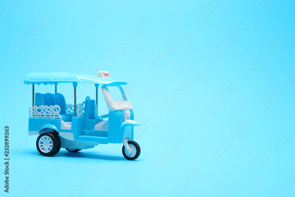 blue tricycle toy or blue auto rickshaw toy on blue paper background with copy space
