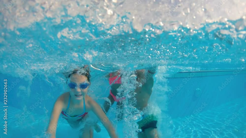 Slow motion shot of three kids jumping into the pool