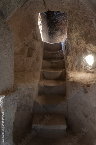 Stairs  from the undergroun city of Derinkuyu. Impressive fairy chimneys of sandstone in the canyon near Cavusin village, Cappadocia, Nevsehir Province in the Central Anatolia Region of Turkey. photo