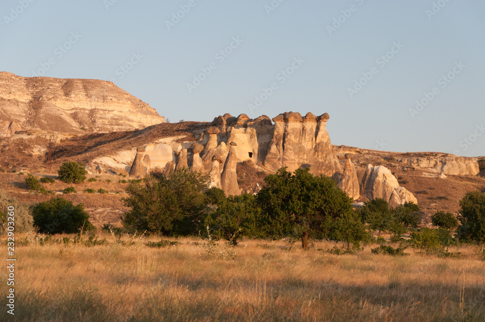 A view from the structure of Cappadocia. Impressive fairy chimneys of sandstone in the canyon near Cavusin village, Cappadocia, Nevsehir Province in the Central Anatolia Region of Turkey. Clear sky.
