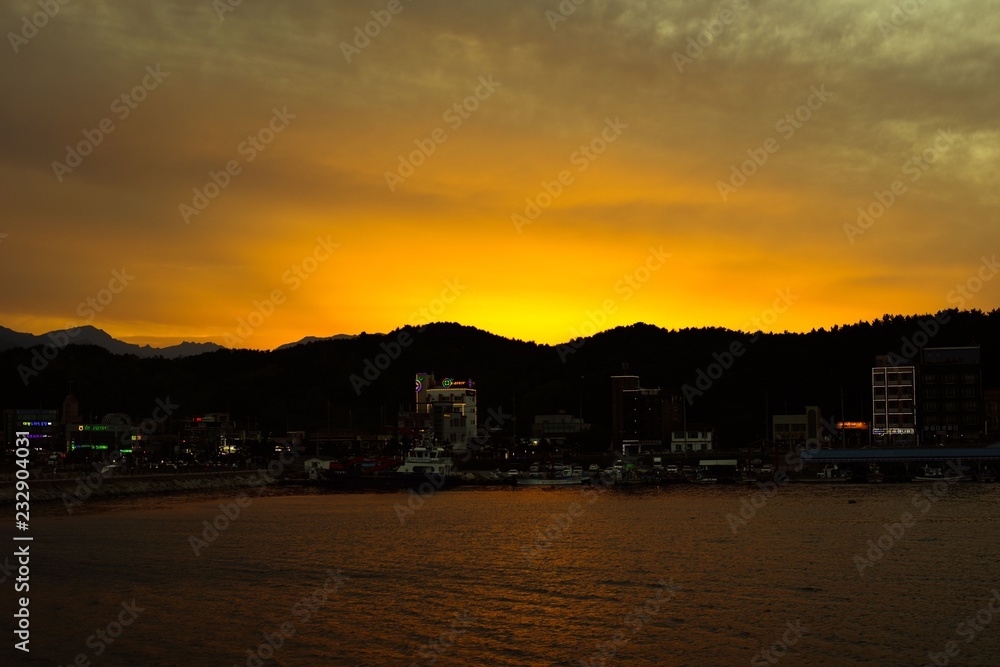 Sunset silhouettes of mountains behind a port village