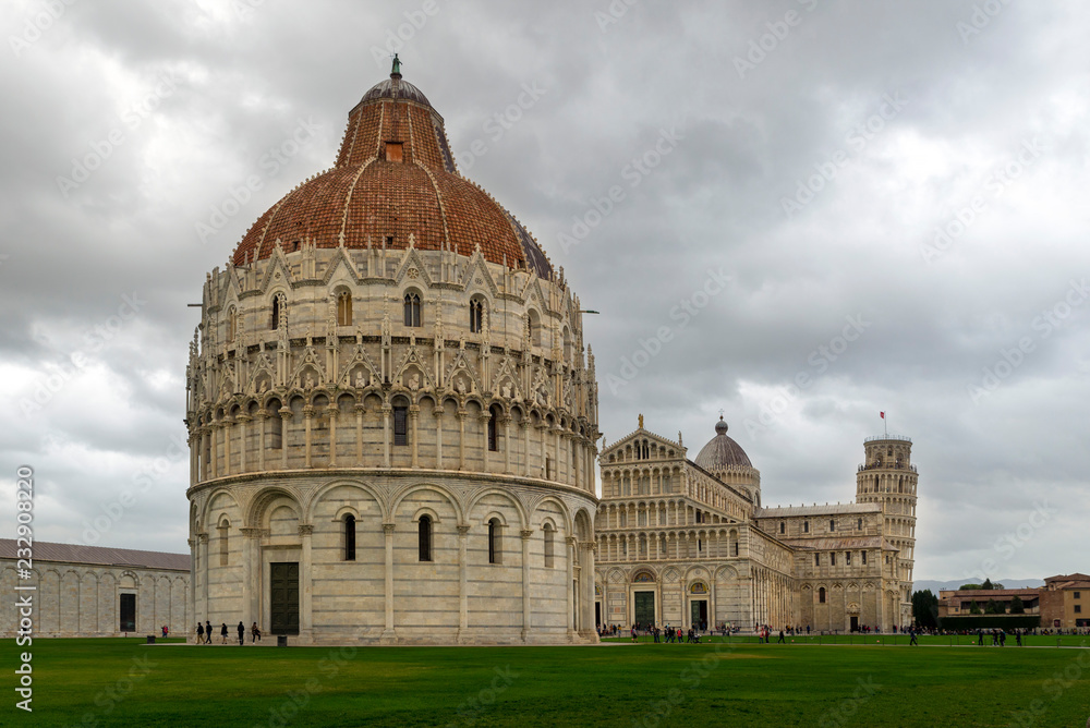 PISA, ITALY - OCTOBER 29, 2018: The Baptistery in the foreground, the Duomo in the center, and the leaning tower in the background on the right