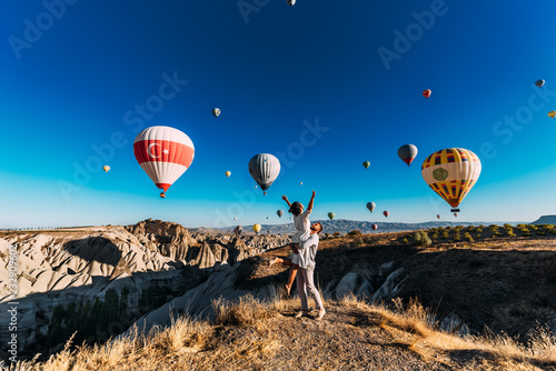 Couple in love among balloons. A guy proposes to a girl. Couple in love in Cappadocia. Couple in Turkey. Honeymoon in the mountains. Man and woman traveling. Flying on balloons. Wedding. Journey. Love photo