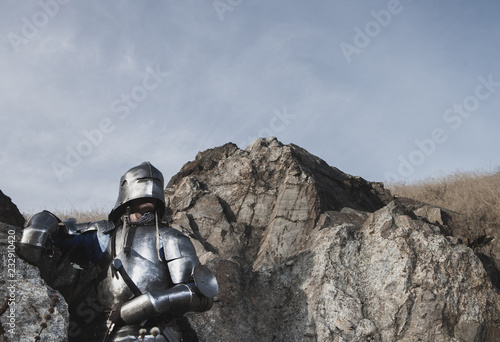 Knight with a sword and in medieval armor on the background of granite stone