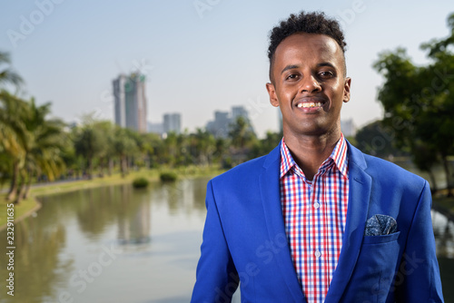 Young handsome African businessman relaxing at the park in Bangk photo