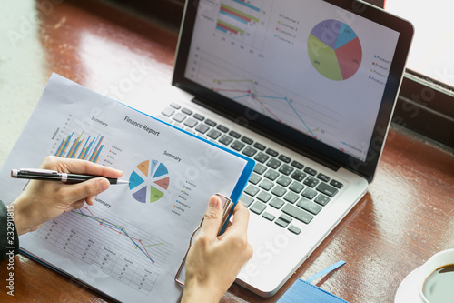 close up of business woman hand working on laptop computer with financial business graph information,  analyzing investment charts. photo